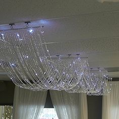 a large chandelier hanging from the ceiling in a room with curtains and drapes