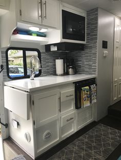 a kitchen with white cabinets and gray tile backsplash, black microwave above the stove