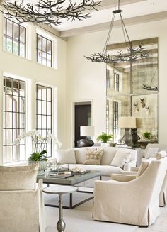 a living room filled with white furniture and lots of window panes above the couch