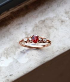 a red and white diamond ring sitting on top of a stone counter next to a window