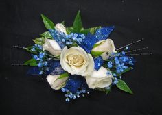 a blue and white boutonniere with flowers on black background, closeup