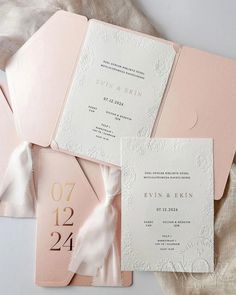 the wedding stationery is laid out on top of each other, including pink and white paper