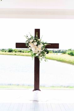 a cross decorated with white flowers and greenery