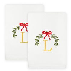 two white towels with red bows and the letter l on them, both have gold lettering