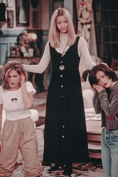 two girls and one boy are standing in front of a bed with their hands on their head