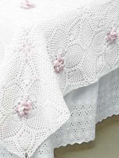 a white lace tablecloth with pink flowers on it's edges and crochet doily