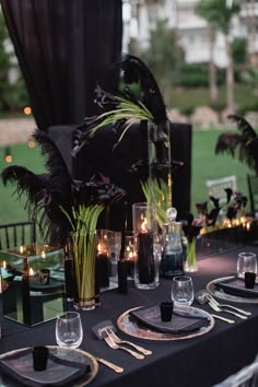 the table is set with black and gold place settings, silverware, candles, and flowers