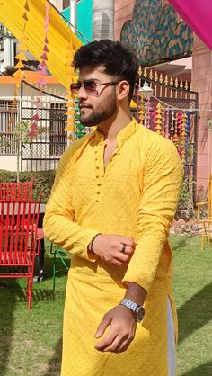 a man standing in front of a red bench wearing a yellow shirt and white pants