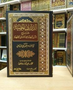 an arabic book is sitting on a table in front of bookshelves with many different types of books