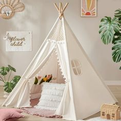 a teepee tent in the corner of a room with pink pillows and other decorations