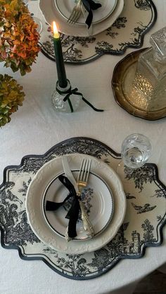 the table is set with black and white plates, silverware, and candlesticks