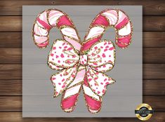 a pink and white candy cane with gold glitters on it's bow is shown in front of a wooden wall