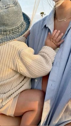 a woman holding a baby in her lap while wearing a blue and white striped shirt