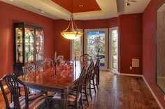 a dining room with red walls and stained glass windows, wood flooring and wooden table surrounded by chairs