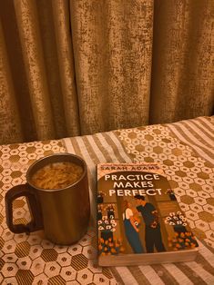 a cup of coffee next to a book on a bed