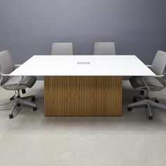 an office table with four chairs and a white board on the top, in front of a gray wall