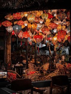 many lanterns are hanging from the ceiling above tables and chairs