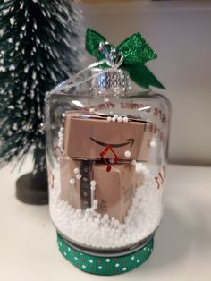 a christmas ornament in a glass container with snow around it