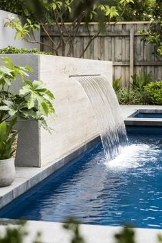 an outdoor pool with water flowing from it's sides and plants growing on the side