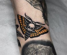 a close up of a person's arm with a butterfly and skull on it