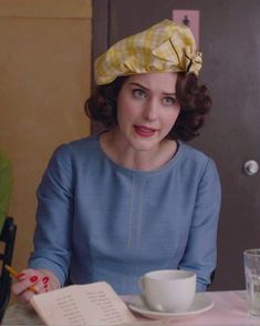 a woman sitting at a table with a cup and saucer