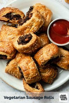 a white plate topped with pastries next to a bowl of ketchup and dipping sauce