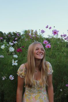 a woman standing in front of flowers smiling