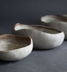 three white bowls sitting on top of a gray surface