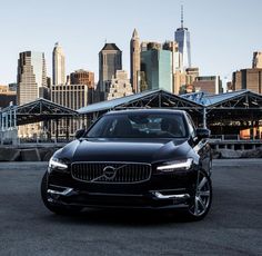 a black car parked in front of a city skyline