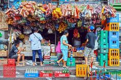 people are shopping at an outdoor market with many items for sale on the street corner