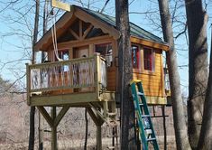 a tree house in the woods with stairs leading to it and a ladder going up