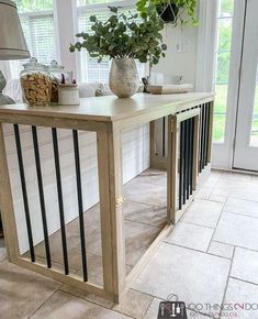 a table with some plants on top of it in front of a door and windows