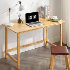 a laptop computer sitting on top of a wooden desk next to a lamp and chair