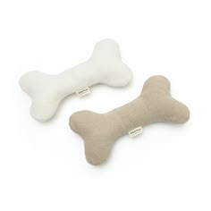 two bone shaped pillows are shown on a white background, one is made out of wool and the other has a dog bone