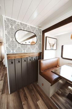 the interior of an rv with wood flooring and wallpaper, including a bench