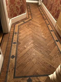 a wooden floor in a room with red wallpaper