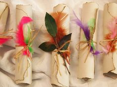 four rolls of paper with feathers tied to them