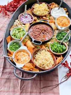 a large pan filled with different types of food on top of a red table cloth