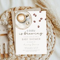 a baby is brewing shower with a teddy bear next to it and a cup of coffee