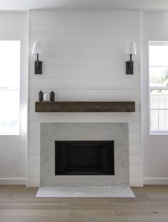 an instagram photo of a fireplace in a living room with white walls and wood flooring