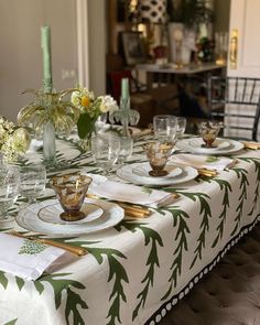 a table set with place settings and flowers in vases on the top, next to candlesticks