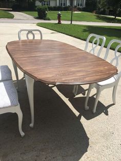 a wooden table and chairs sitting on the side of a road in front of a house