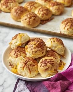 a white plate topped with biscuits next to a tray of other pastries on a table