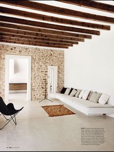 a living room filled with white furniture and stone wall covering it's walls,