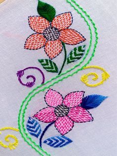 a close up of a embroidery design on a white cloth with flowers and swirls