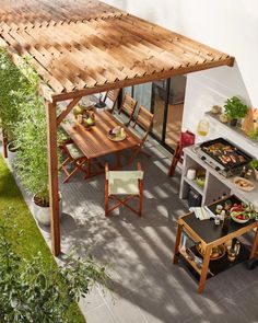 an outdoor dining area with table, chairs and grill on the side of the house