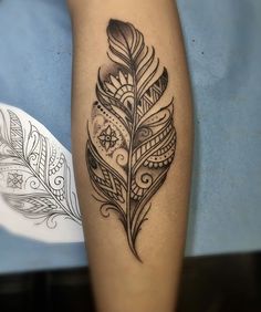 a black and white feather tattoo on the left leg, with an intricate design in the middle