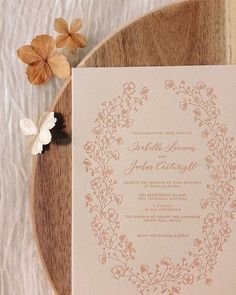 the wedding stationery is laid out on top of a wooden table with flowers and leaves