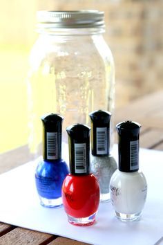 three nail polish bottles sitting on top of a white napkin next to a mason jar