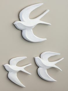 three white birds are on the wall and one is in the shape of a bird